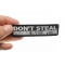 Don't Steal Government Hates Competition Funny Iron on Patch shown on hand for size comparison