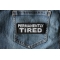 Permanently Tired Patch shown on jeans