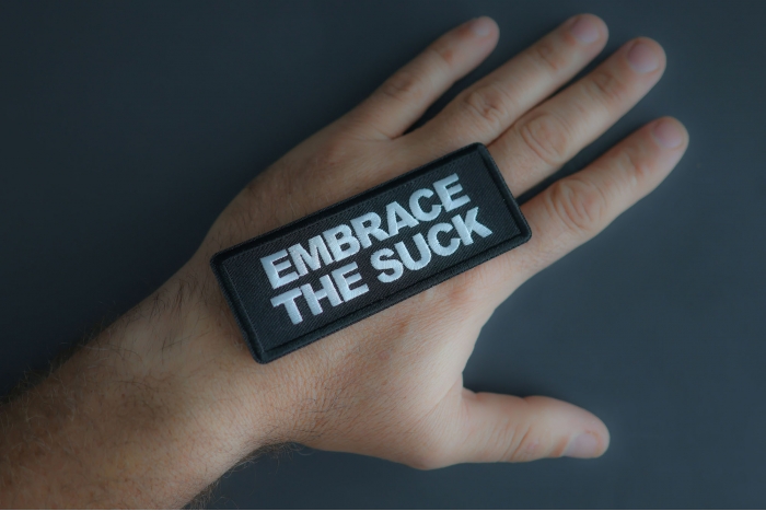Embrace The Suck Patch shown on hand for size comparison