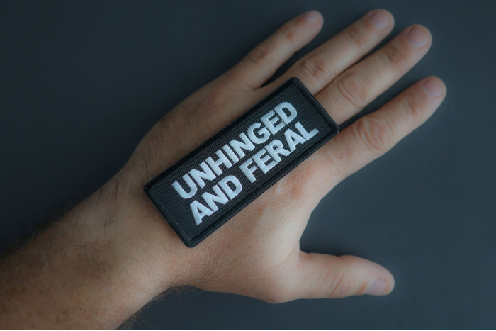 Unhinged And Feral Patch shown on hand for size comparison