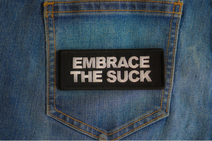 Embrace The Suck Patch shown on jeans