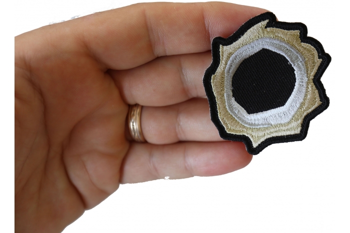 Bullet Hole Patch Green Metal shown on hand for size comparison