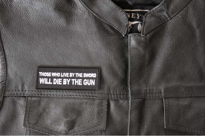Those Who Live by the Sword Will Die By The Gun Patch - 4x1.5 inch - Embroidered Iron on Patch shown on leather vest