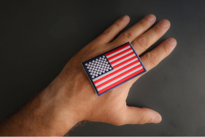 Blue Border American Flag Patch shown on hand for size comparison