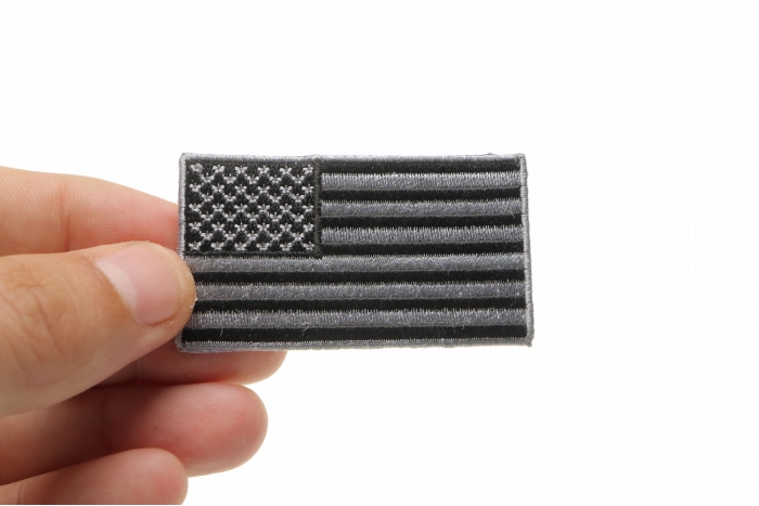 US Flag Patch Black and Gray 2.5 Inch shown on hand for size comparison