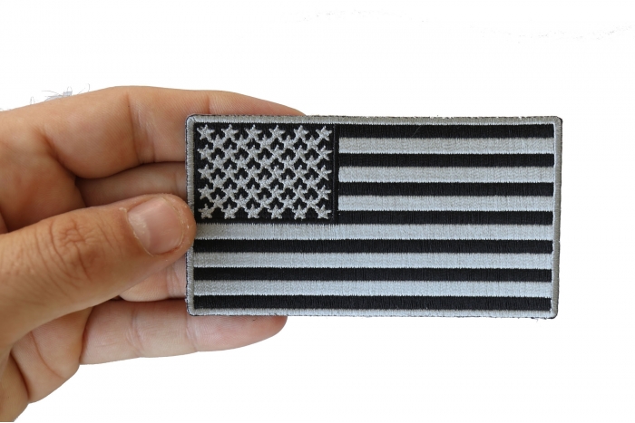 US Flag Patch Black and Gray 4 Inch shown on hand for size comparison