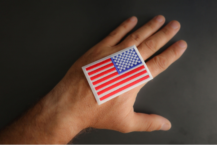 White Border Reversed American Flag Patch shown on hand for size comparison