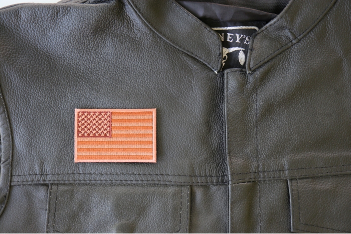 Subdued Brown US Flag Patch - 3x2 inch. Embroidered Iron on Patch shown on leather vest