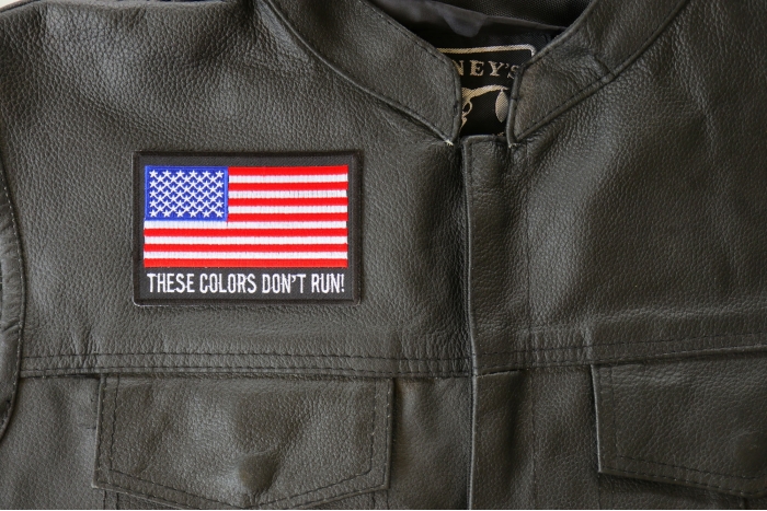 These Colors Don't Run US Flag Patch - 4x2.75 inch. Embroidered Iron on Patch shown on leather vest