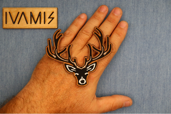 Black Deer Head Patch shown on hand for size comparison
