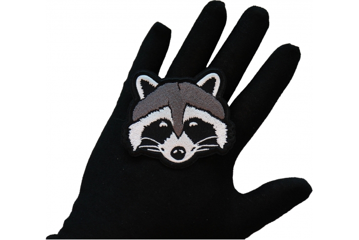 Funny Raccoon Iron on Patch shown on hand for size comparison