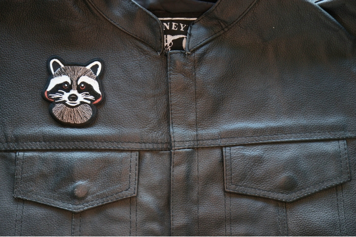 Cheeky Raccoon Iron on Patch shown on leather vest