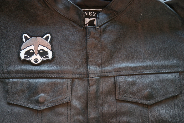 Funny Raccoon Iron on Patch shown on leather vest