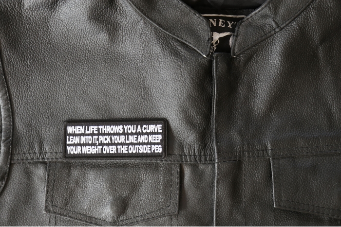 When Life throws you a curve, Lean into it, Pick your line and keep your weight over the outside Peg Patch, Biker Saying Patches shown on leather vest