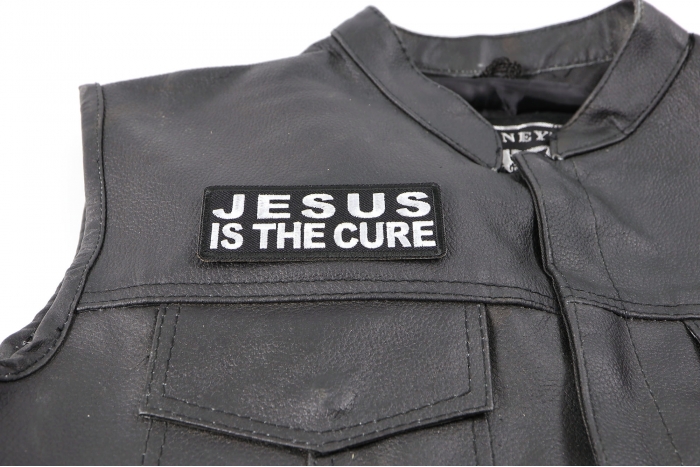 Jesus is The Cure Patch - 4x1.5 inch. Embroidered Iron on Patch shown on leather vest