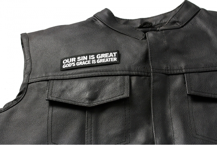 Our Sin Is Great Gods Grace Is Greater Patch - 4x1.25 inch. Embroidered Iron on Patch shown on leather vest