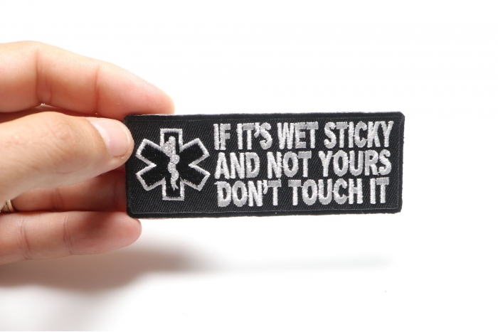 If It's Wet Sticky and Not Yours Fun EMT Patch shown on hand for size comparison