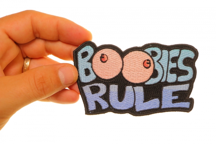 Boobies Rule Funny Iron on Patch shown on hand for size comparison