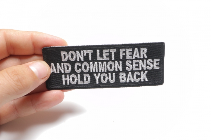 Don't Let Fear and Common Sense Hold You Back Funny Iron on Patch shown on hand for size comparison