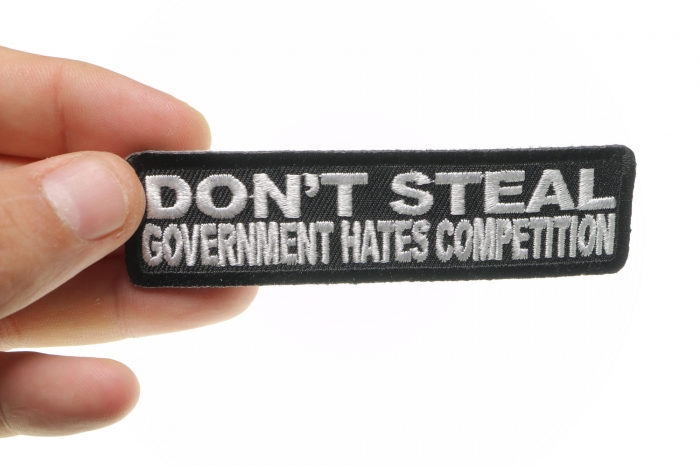 Don't Steal Government Hates Competition Funny Iron on Patch shown on hand for size comparison