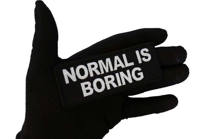 Normal is Boring Funny Iron on Patch shown on hand for size comparison