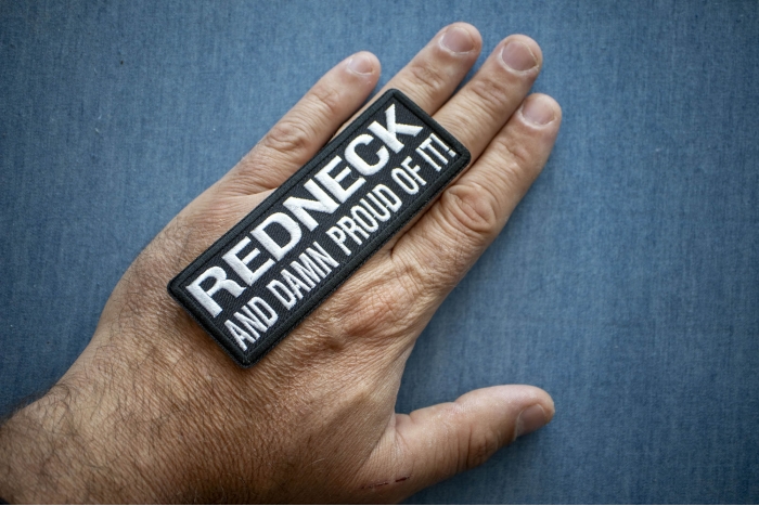 Redneck and Damn Proud Of It! Funny Iron on Patch shown on hand for size comparison
