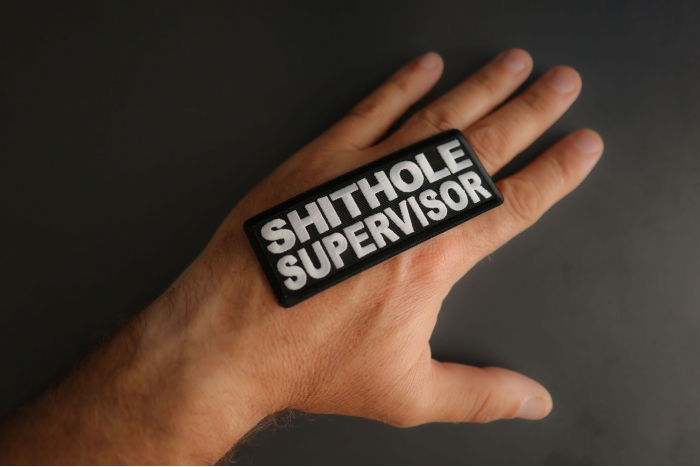 Shithole Supervisor Patch shown on hand for size comparison