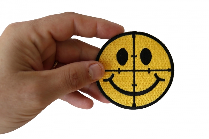 Sniper Scope Smiley Face Funny Iron on Patch shown on hand for size comparison