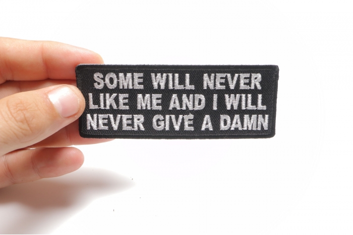 Some Will Never Like Me and I Will Never Give A Damn Funny Iron on Patch shown on hand for size comparison