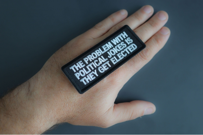 The Problem With Political Jokes Is They Get Elected Patch shown on hand for size comparison