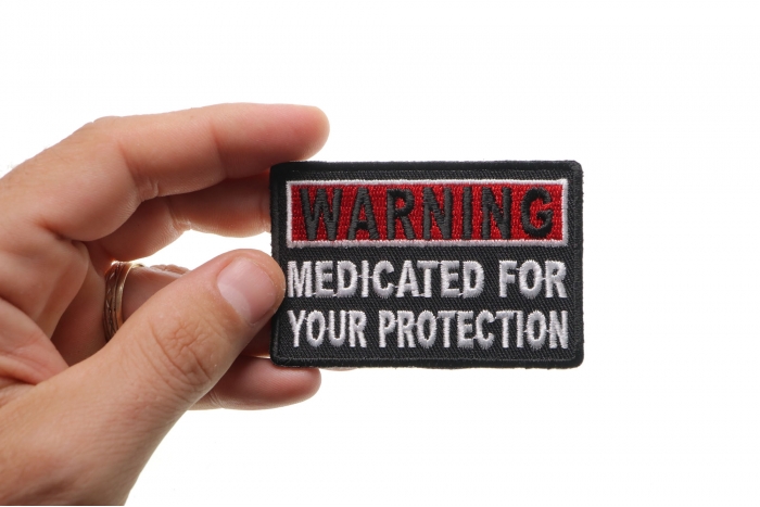 Warning Medicated For Your Protection Funny Iron on Patch shown on hand for size comparison