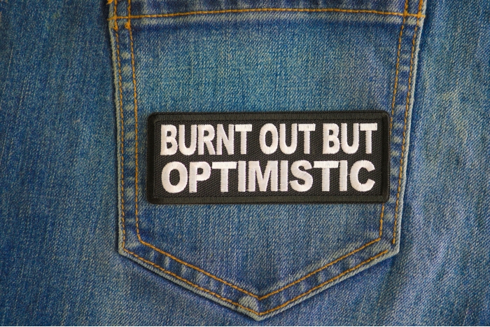 Burnt Out But Optimistic Patch shown on jeans