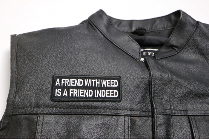 A Friend with Weed is a Friend Indeed Patch - 4x1.5 inch. Embroidered Iron on Patch shown on leather vest