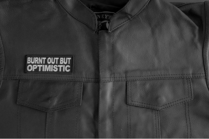 Burnt Out But Optimistic Patch shown on leather vest