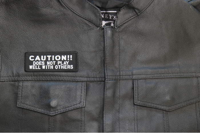 Caution Does Not Play Well With Others Patch - 4x2 inch. Embroidered Iron on Patch shown on leather vest