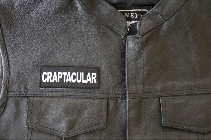 Craptacular Patch - 4x1.5 inch. Embroidered Iron on Patch shown on leather vest