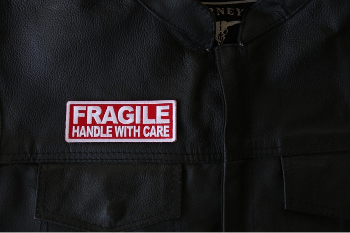 Fragile Handle with Care Patch - 4x1.5 inch - Embroidered Iron on Patch shown on leather vest