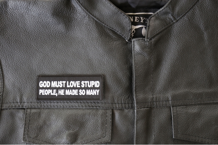 God Must Love Stupid People, He Made So Many Patch - 4x1.5 inch - Embroidered Iron on Patch shown on leather vest