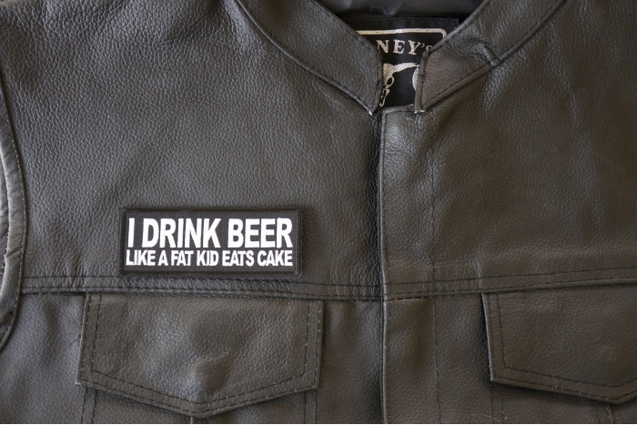 I Drink Beer Like a Fat Kid Eats Cake Patch - 4x1.5 inch. Embroidered Iron on Patch shown on leather vest