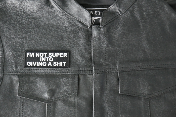 I'm not Super into Giving a shit Patch - 4x1.5 inch - Embroidered Iron on Patch shown on leather vest