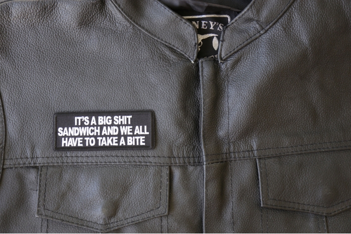 It's a Big Shit Sandwich and We all have to take a Bite Patch - 4x1.5 inch - Embroidered Iron on Patch shown on leather vest