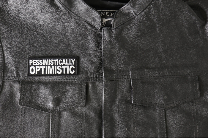 Pessimistically Optimistic Patch - 4x1.5 inch - Embroidered Iron on Patch shown on leather vest