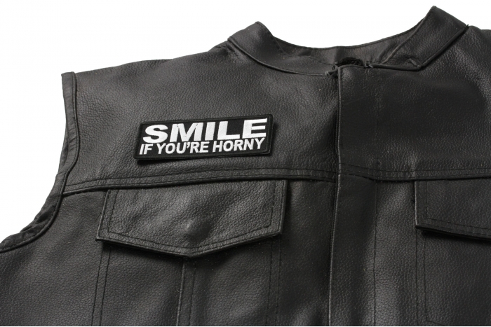Smile If You're Horny Patch - 4x1.5 inch. Embroidered Iron on Patch shown on leather vest