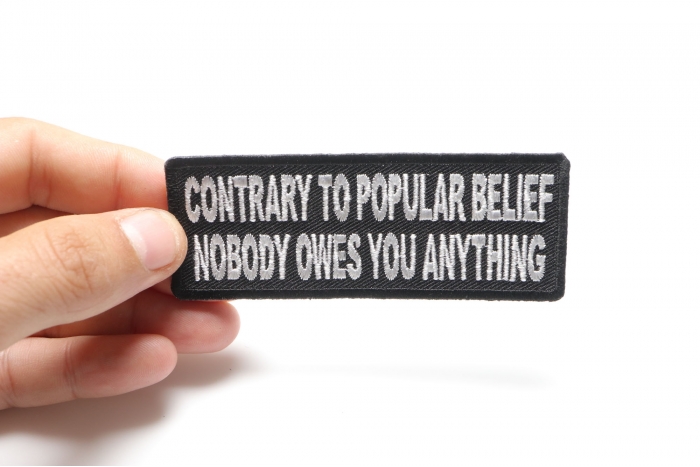 Contrary To Popular Belief Nobody Owes You Anything Iron on Morale Patch shown on hand for size comparison