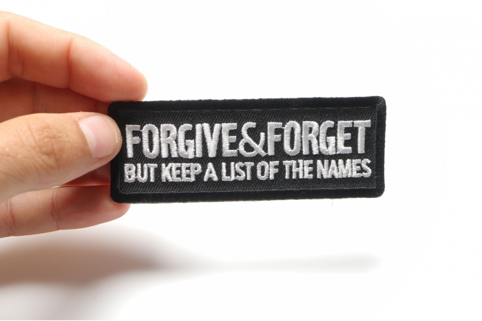 Forgive and Forget But Keep A List Of The Names Iron on Morale Patch shown on hand for size comparison