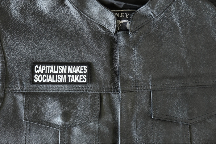 Capitalism Makes Socialism Takes Patch - 4x1.5 inch - Embroidered Iron on Patch shown on leather vest