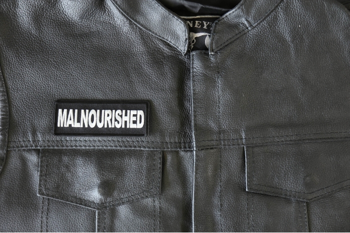 Malnourished Patch - 4x1.5 inch - Embroidered Iron on Patch shown on leather vest
