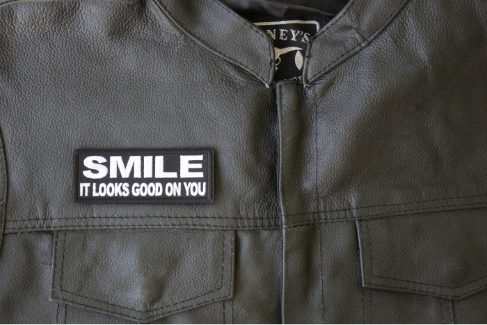 Smile It Looks Good on You Patch - 4x1.5 inch - Embroidered Iron on Patch shown on leather vest