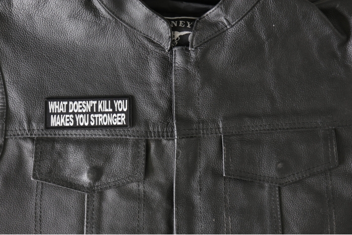 What Doesn't Kill You Makes You Stronger Patch - 4x1.5 inch - Embroidered Iron on Patch shown on leather vest