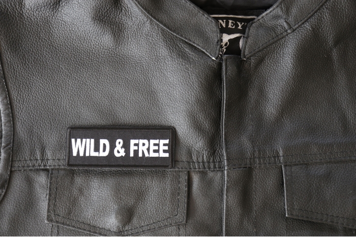 Wild and Free Patch - 4x1.5 inch - Embroidered Iron on Patch shown on leather vest
